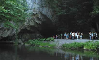 Eingang der Grotte von Han sur Lesse mit vielen wartenden Touristen, natürliche Felsen und Besucherzentrum im Hintergrund