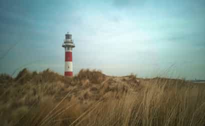 Leuchtturm von Nieuwpoort an der belgischen Nordseeküste, aufgenommen bei Tageslicht mit blauem Himmel im Hintergrund