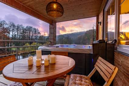 1091185 Jacuzzi auf einer Terrasse bei Sonnenuntergang mit Blick auf einen Fluss