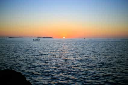 Stimmungsvoller Sonnenuntergang über dem Meer auf Ibiza, goldene Lichtreflexe auf dem Wasser