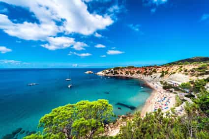 Blick auf den Strand und die Bucht von Cala d'Hort auf Ibiza bei leicht bewölktem Himmel