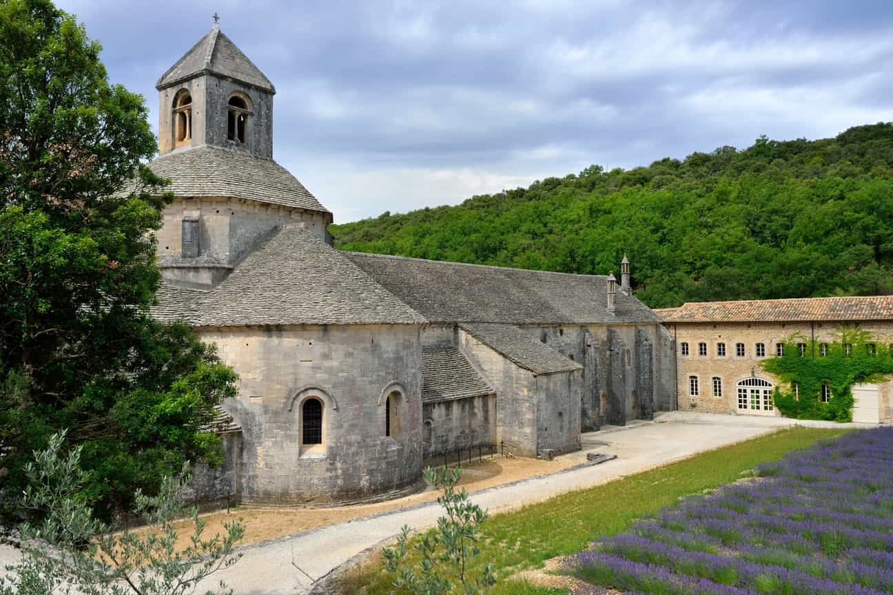 Außenansicht der Abbaye Notre-Dame de Sénanque in der Provence, umgeben von Natur und Lavendelfeldern.