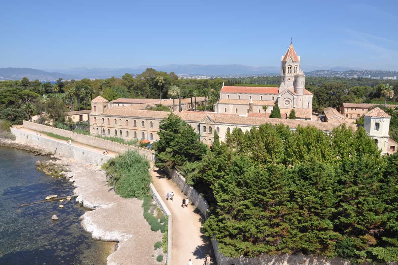 Luftaufnahme der Abbaye de Lérins mit Klostergebäuden, grüner Umgebung und Blick auf das Mittelmeer.