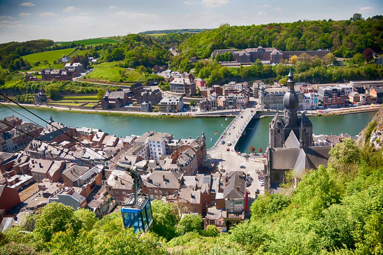 Panoramablick über die belgische Stadt Dinant mit Fluss, Altstadt und umgebender Hügellandschaft.