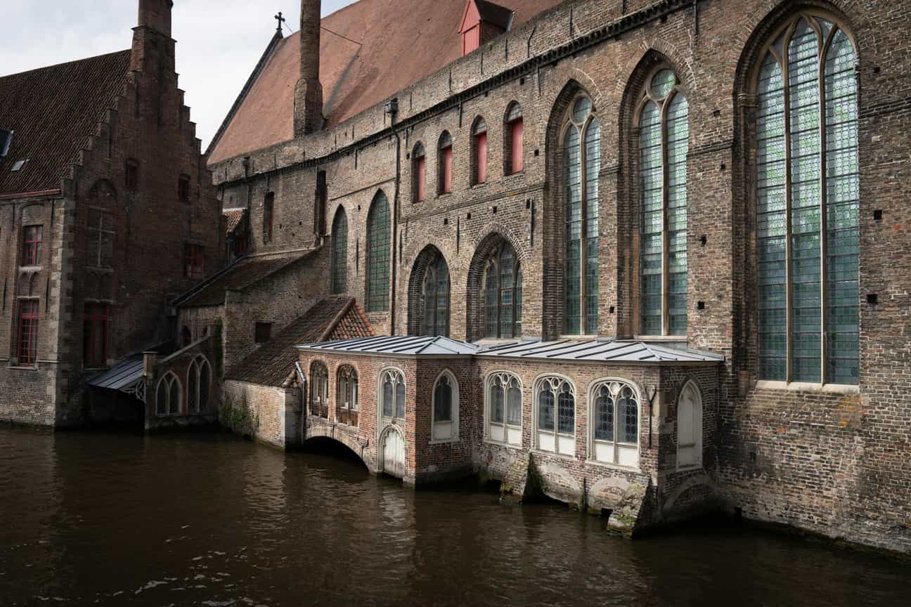 Blick vom Wasser auf die Rückseite eines alten Backsteinhauses in Brügge mit charakteristischer roter Backsteinfassade und charmanten Details
