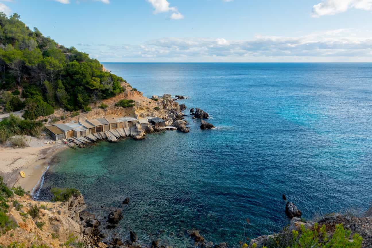 Panoramaaufnahme der Cala d’en Serra mit türkisblauem Wasser, Felsen und umgebender Natur