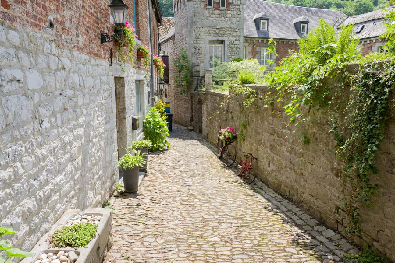 Gerade Kopfsteinpflasterstraße in Durbuy mit Haus auf der linken Seite und efeubewachsener Mauer rechts