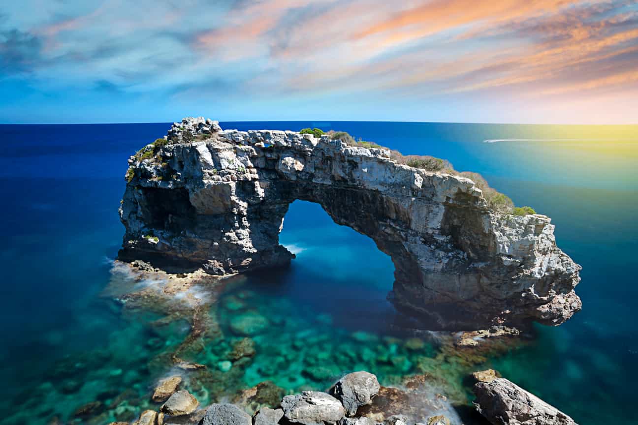 Es Pontas Natursteinbogen im Meer bei Cala Llombards auf Mallorca, fotografiert vom Ufer aus