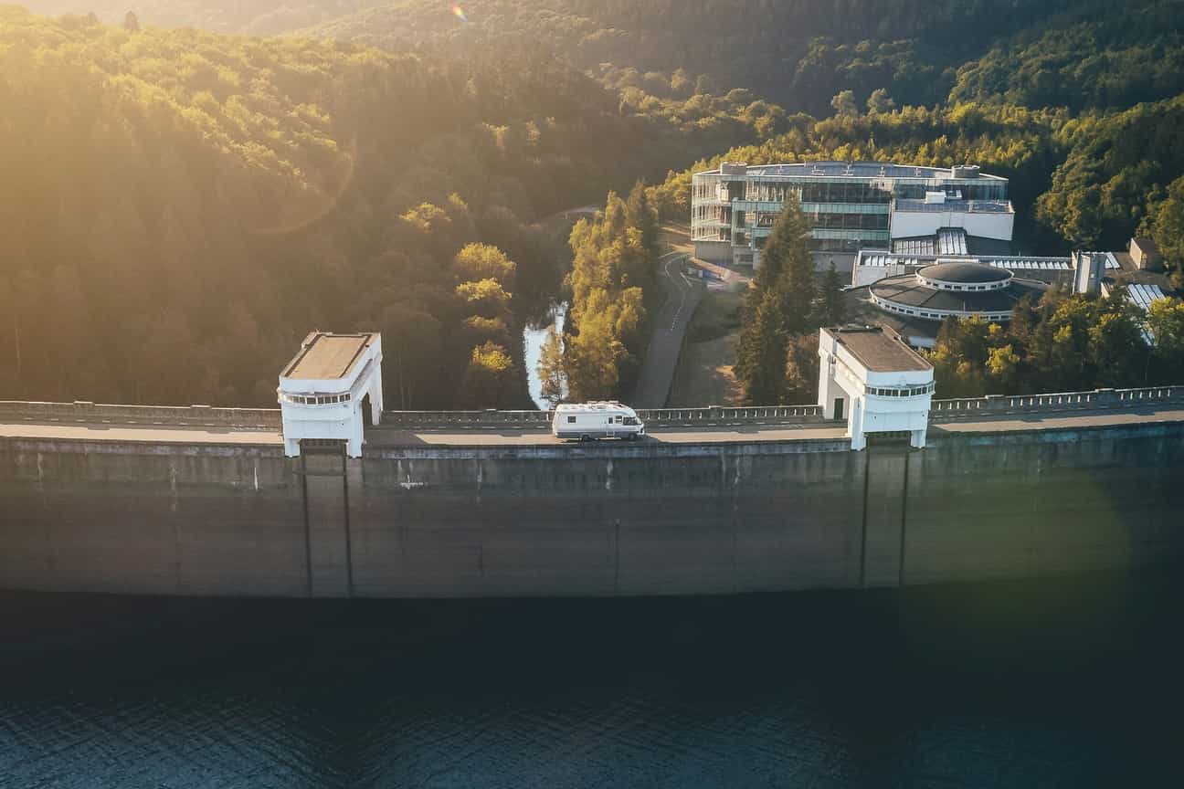 Camper steht an der Talsperre Eupen mit Blick auf Wasser und umliegenden Wald