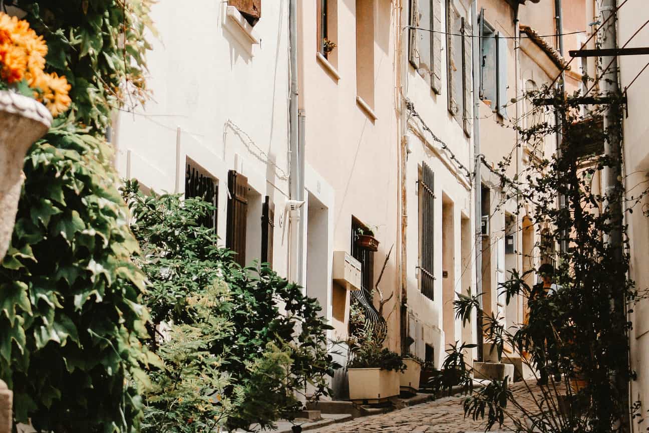 Schmale Gasse in Saint-Rémy-de-Provence mit Efeubewuchs, bleichen Hausfassaden und nostalgischer Straßenlaterne