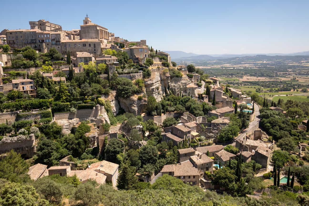 Blick auf das Dorf Gordes in Südfrankreich, das sich terrassenförmig an den Hang schmiegt – mit alten Steinhäusern und weitem Ausblick