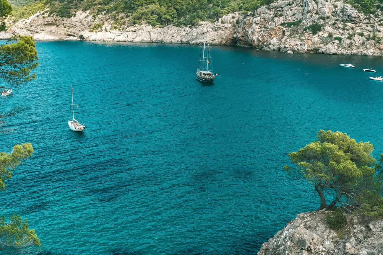 Weitwinkelaufnahme einer ruhigen Bucht auf Ibiza mit einem Boot im klaren Mittelmeerwasser