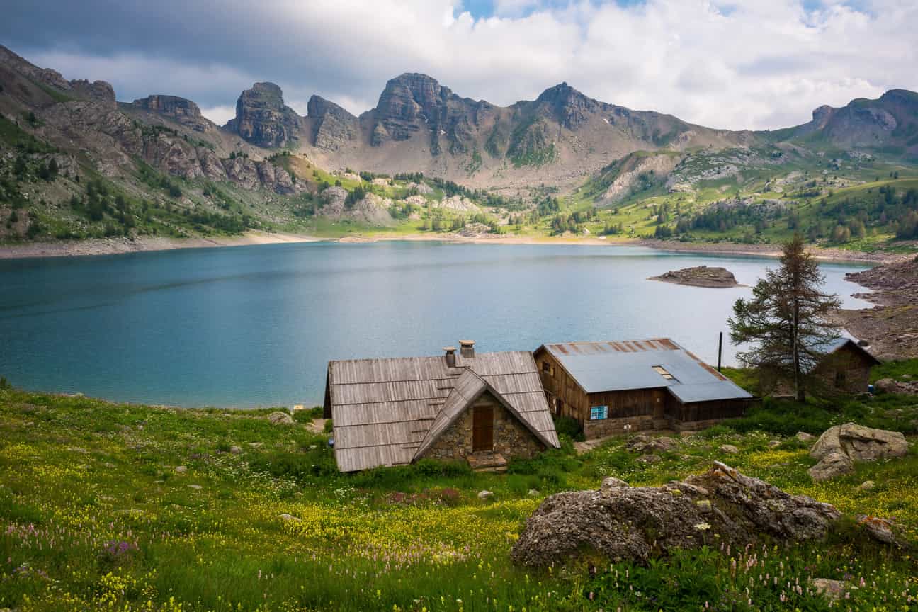 Blick vom Ufer auf den Lac d’Allos inmitten der französischen Alpen, ruhiges Wasser und umliegende Berge