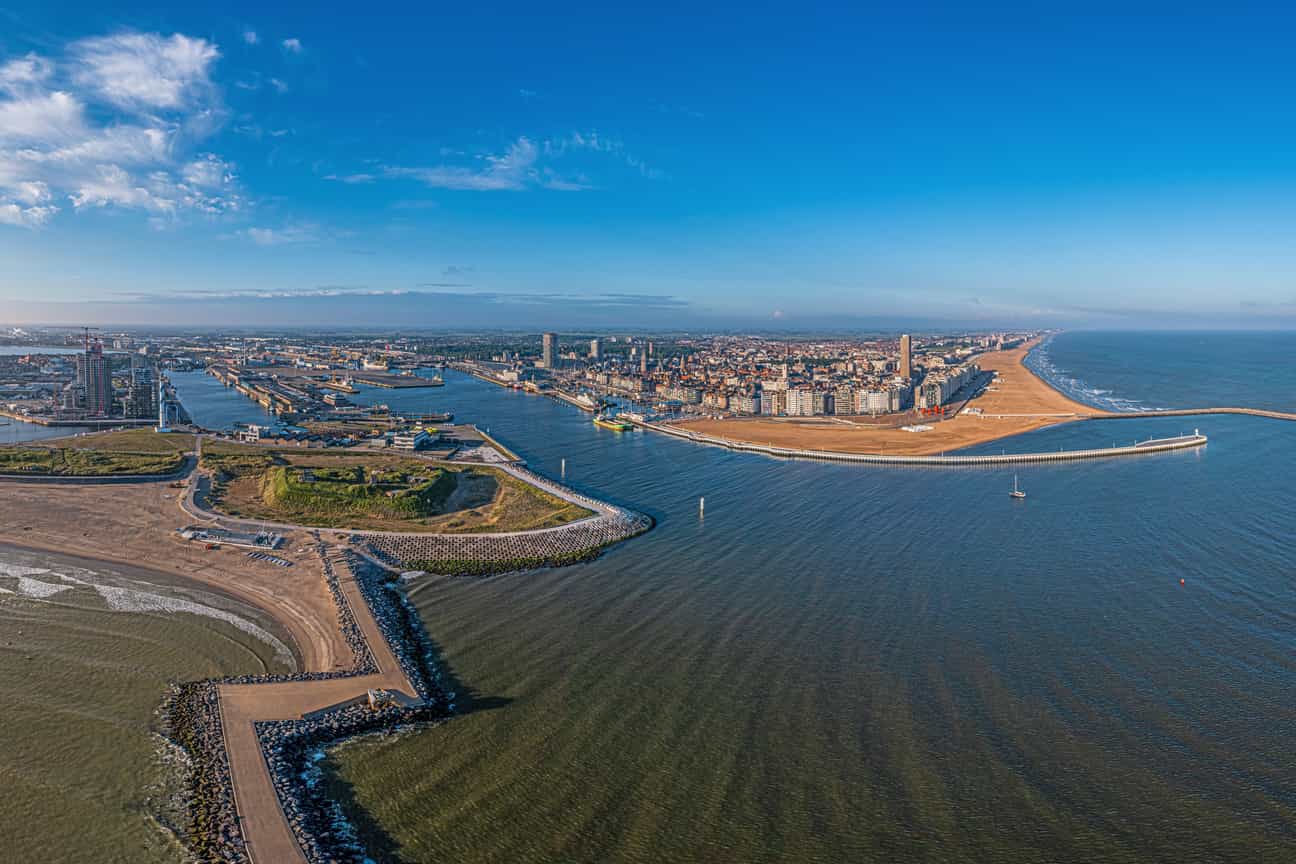 Drohnenaufnahme des Hafens und der Skyline von Ostende bei klarem Himmel und Morgensonne