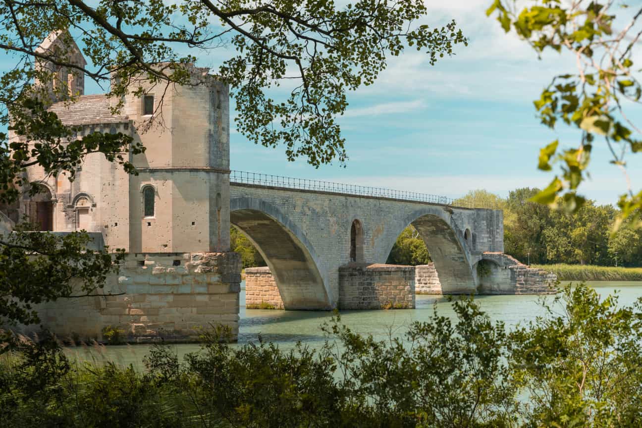 Teilansicht der Pont d’Avignon, eingerahmt von grünem Gebüsch – historisches Wahrzeichen in Südfrankreich