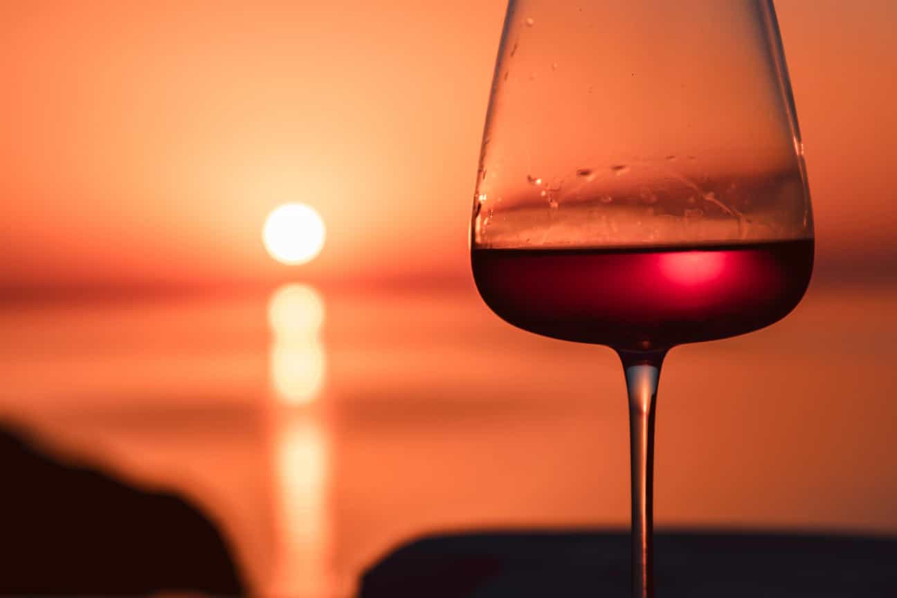 Glas Rotwein im Abendlicht während eines Sonnenuntergangs