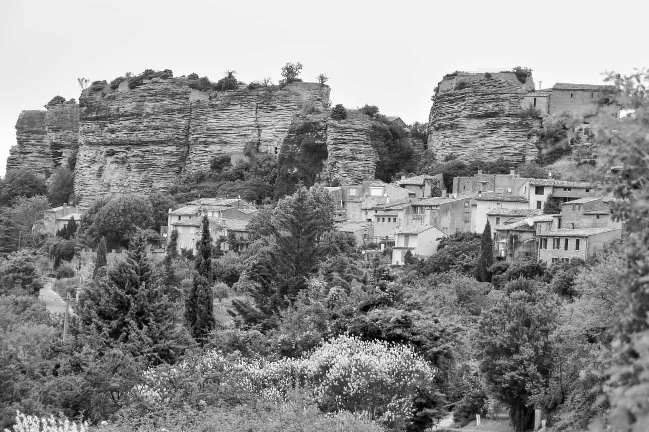 Panoramablick auf das Dorf Saignon mit traditionellen Häusern und markanten Felsen im Hintergrund unter klarem Himmel