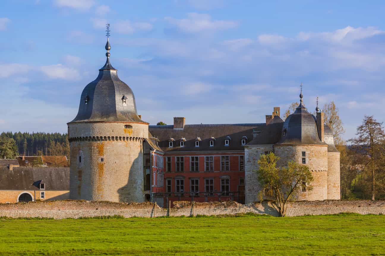 Schloss Lavaux-Sainte-Anne mit Hauptgebäude, Rasen und Himmel bei flach stehender Sonne