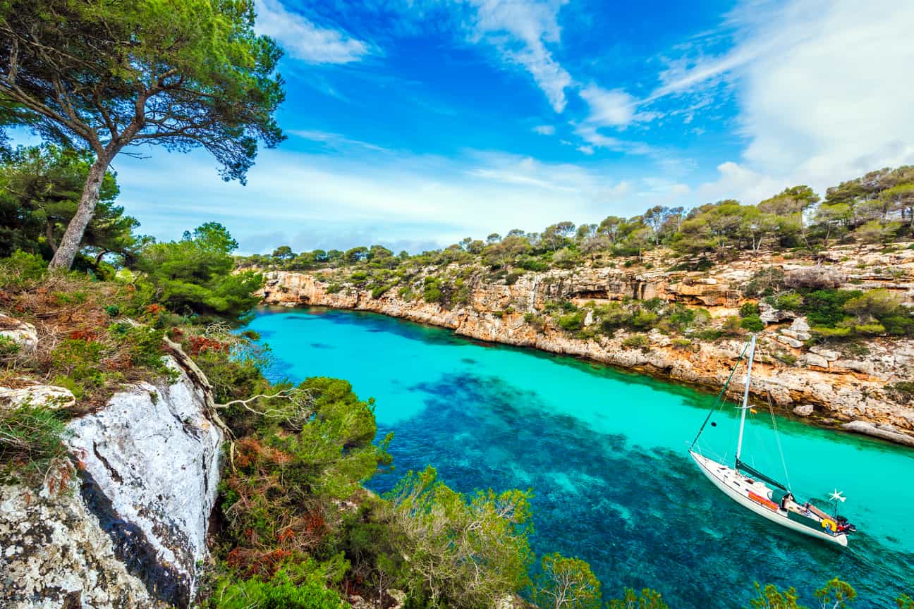 Segelboot vor Anker in der Bucht Cala Pi auf Mallorca mit klarem Wasser und Felsen