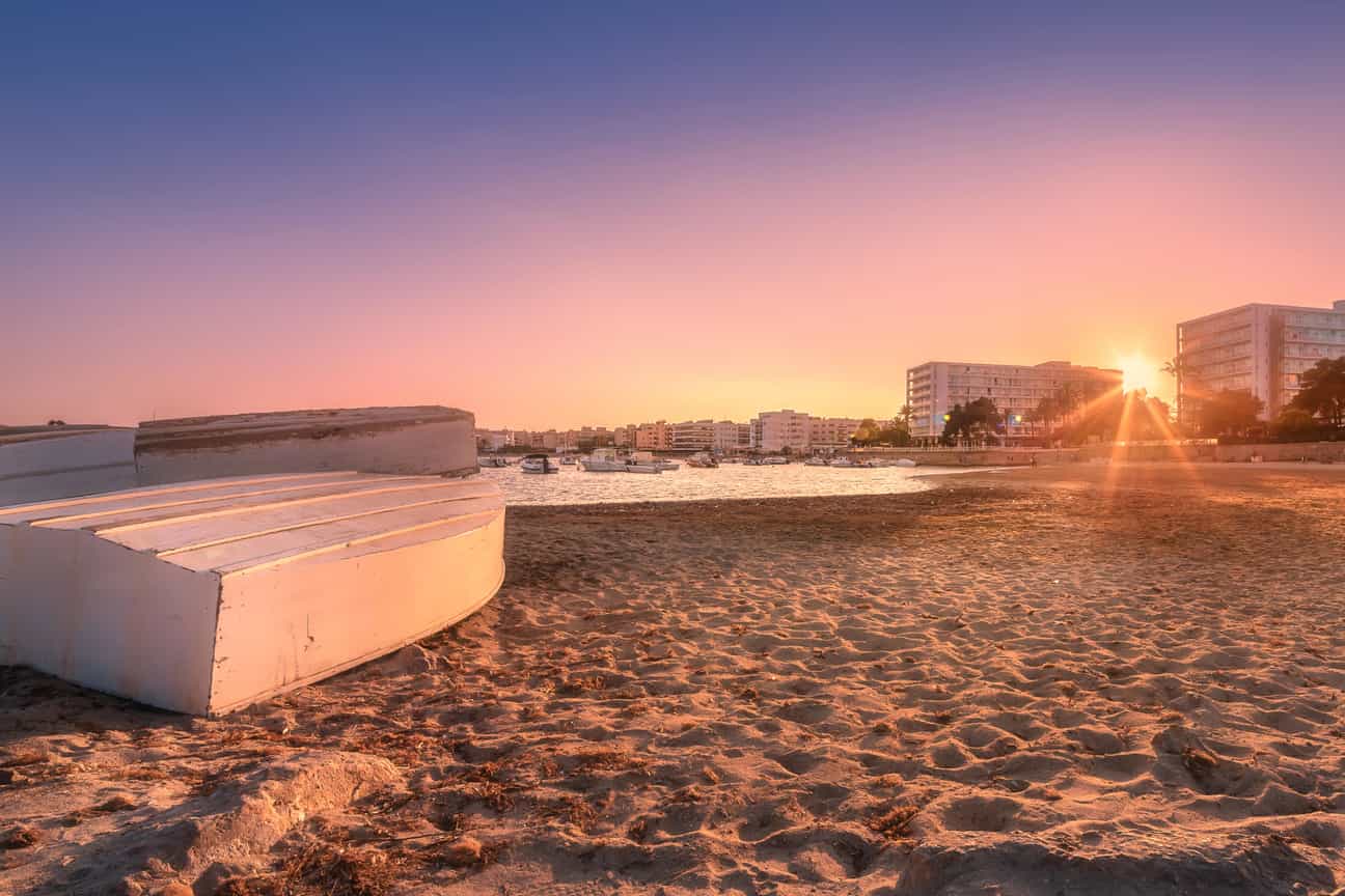Sonnenuntergang am Sandstrand von Ibiza, mit pastellfarbenem Himmel und den letzten Sonnenstrahlen des Tages, während die Wellen sanft ans Ufer rollen