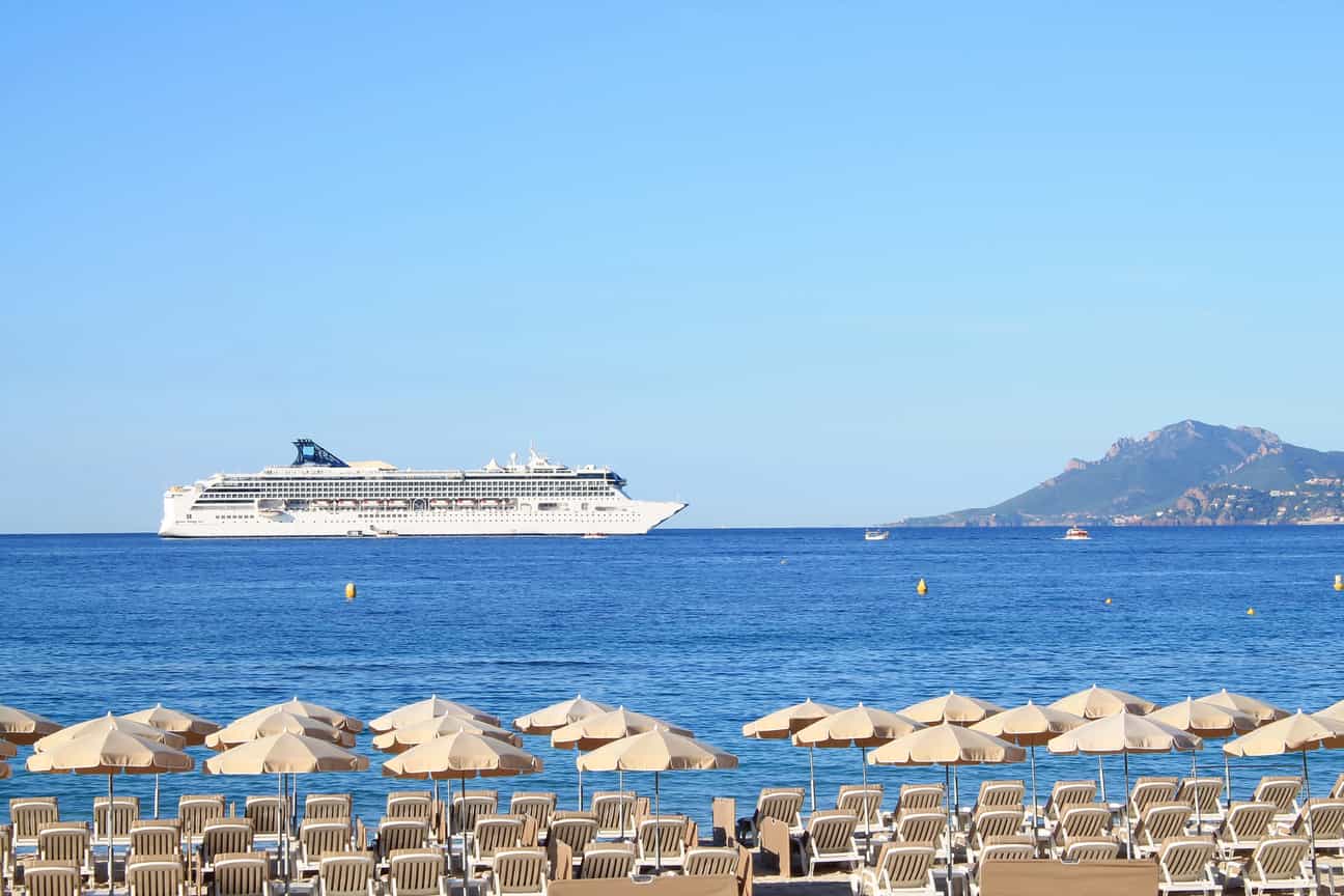 Sandstrand an der Promenade La Croisette in Cannes mit Sonnenliegen, Sonnenschirmen und Blick auf das Mittelmeer.