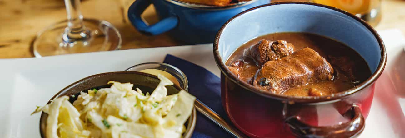 Traditionelles belgisches Gericht mit Gulasch, knusprigen Pommes, Krautsalat und einem Glas Bier auf einem Holztisch
