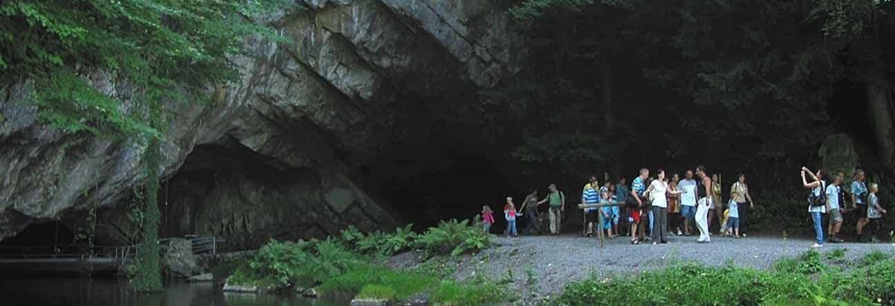 Eingang der Grotte von Han sur Lesse mit vielen wartenden Touristen, natürliche Felsen und Besucherzentrum im Hintergrund