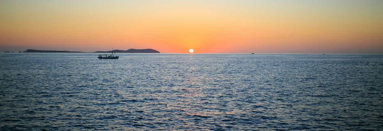 Stimmungsvoller Sonnenuntergang über dem Meer auf Ibiza, goldene Lichtreflexe auf dem Wasser