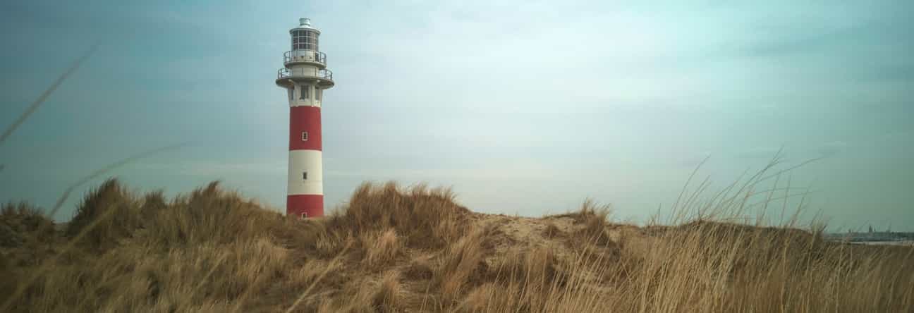 Leuchtturm von Nieuwpoort an der belgischen Nordseeküste, aufgenommen bei Tageslicht mit blauem Himmel im Hintergrund